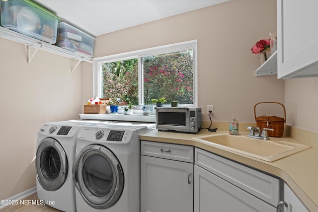 washroom with cabinet space, a toaster, washing machine and dryer, and a sink