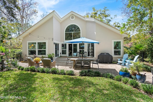 back of house featuring a patio area, stucco siding, and a lawn