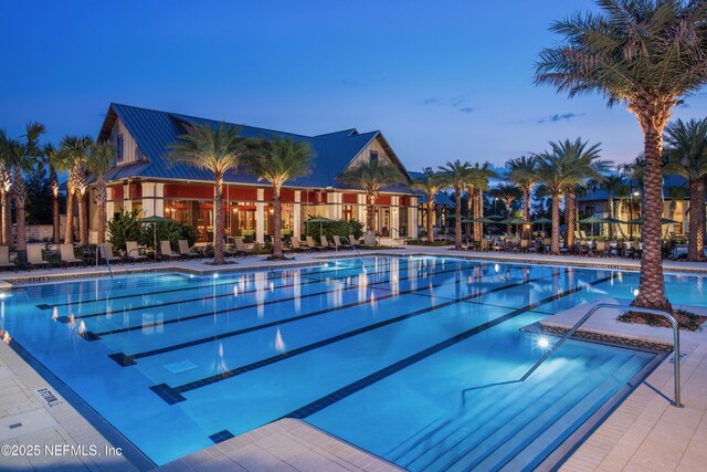 pool at dusk with a community pool and a patio