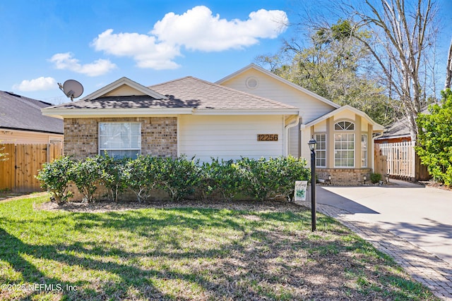 view of front of house featuring brick siding, a shingled roof, a front lawn, fence, and a gate