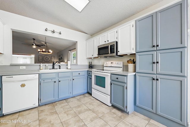 kitchen featuring blue cabinetry, lofted ceiling, light tile patterned floors, white appliances, and a sink