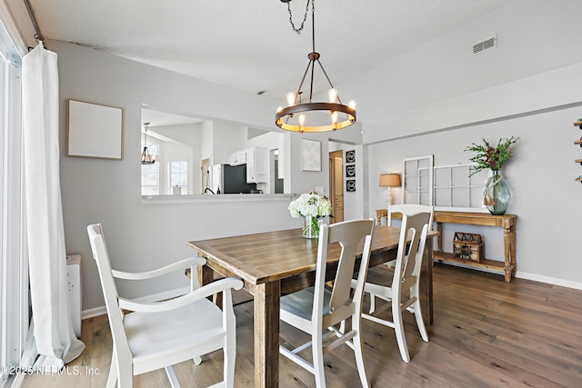 dining room featuring an inviting chandelier, wood finished floors, visible vents, and baseboards