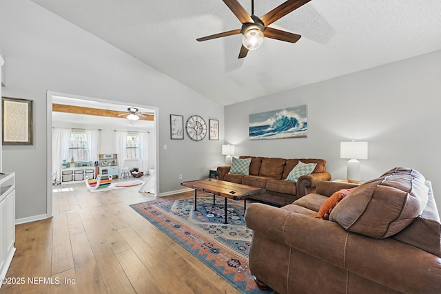 living area with baseboards, lofted ceiling, ceiling fan, light wood-style floors, and a textured ceiling