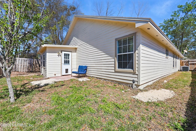 rear view of property featuring cooling unit, a lawn, and fence