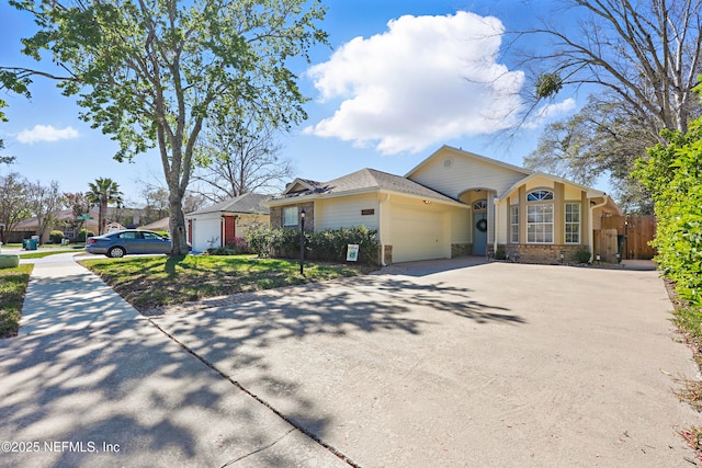 view of front of home with a garage, stone siding, concrete driveway, and fence