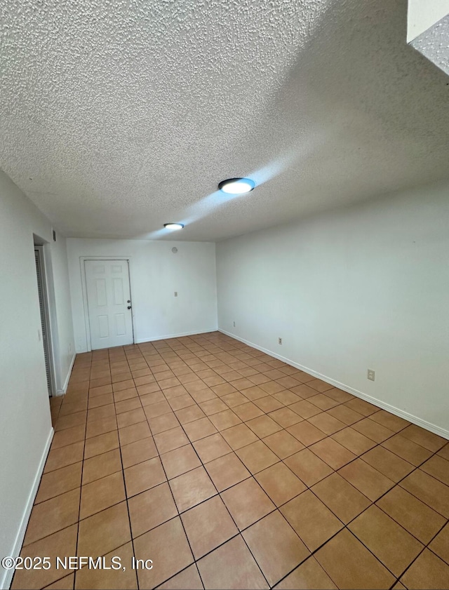 unfurnished room with a textured ceiling and baseboards