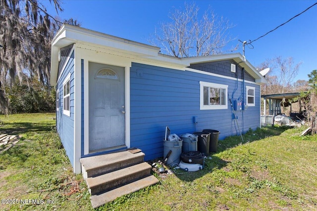 rear view of property featuring entry steps and a yard