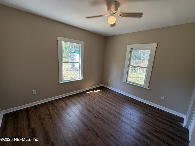 spare room with baseboards, a healthy amount of sunlight, dark wood finished floors, and a ceiling fan