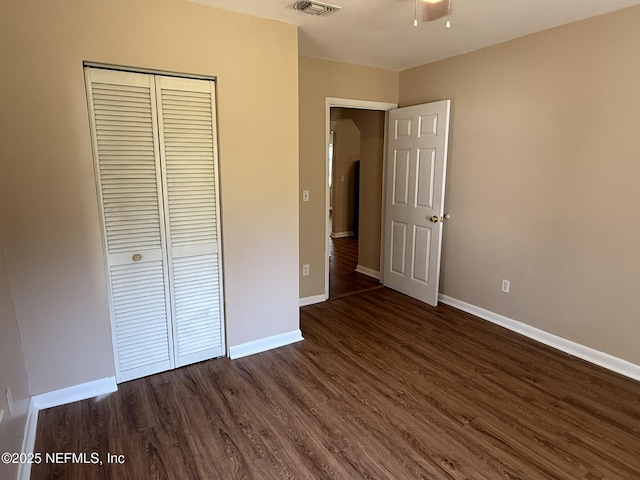 unfurnished bedroom with a closet, baseboards, visible vents, and dark wood-style floors