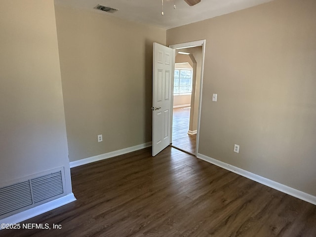 spare room with visible vents, baseboards, dark wood-style floors, and a ceiling fan