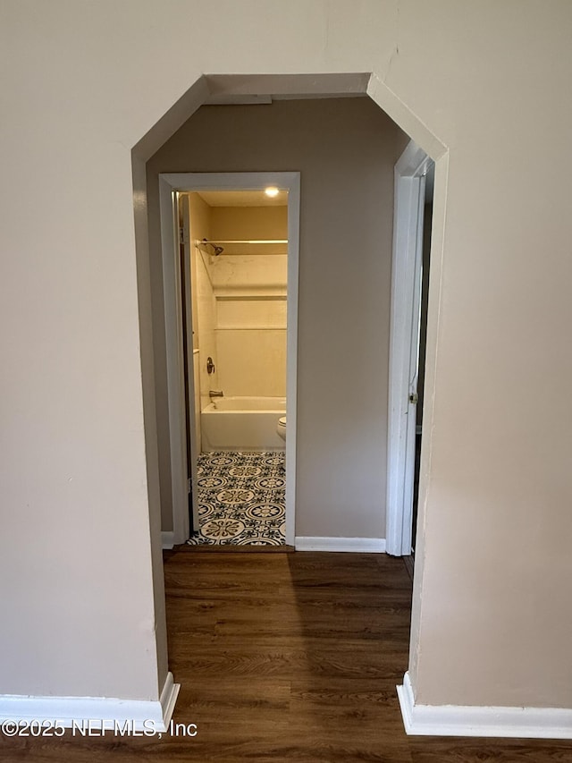 corridor with baseboards and wood finished floors