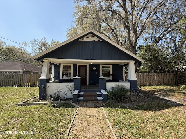 view of front facade with a porch, a front yard, and fence