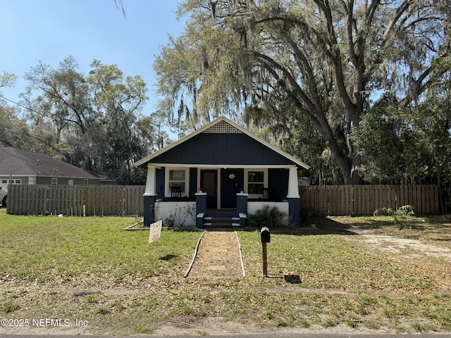 view of front facade with a porch, fence, and a front lawn