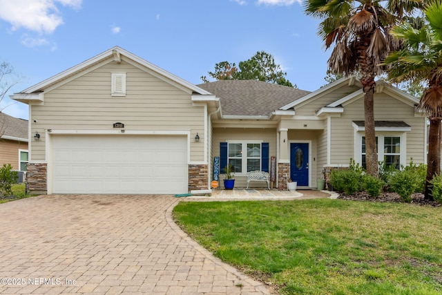 view of front of property with a front lawn, decorative driveway, stone siding, roof with shingles, and a garage