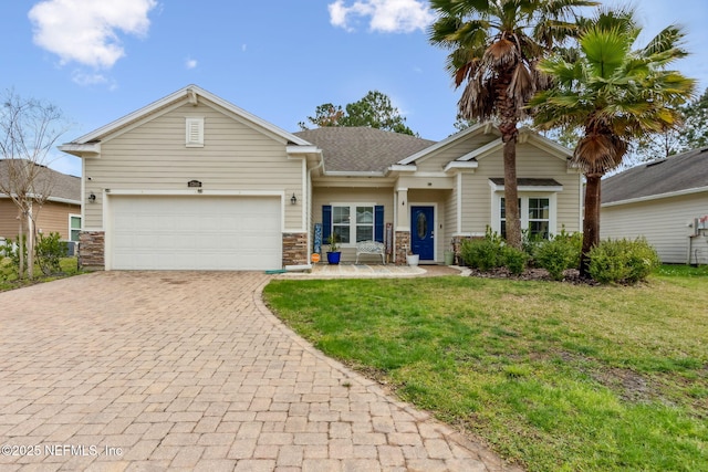 view of front of home with a front yard, roof with shingles, an attached garage, stone siding, and decorative driveway