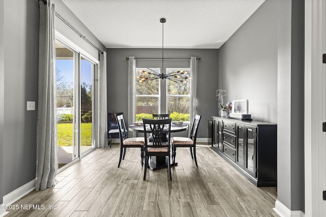 dining space featuring baseboards, a notable chandelier, a healthy amount of sunlight, and wood finished floors