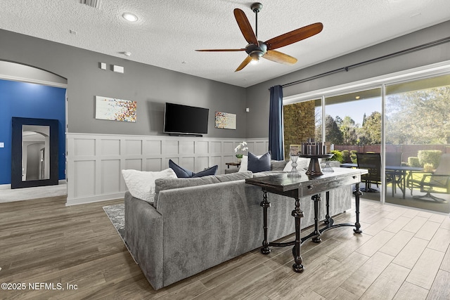 living area with a decorative wall, wainscoting, and wood finished floors