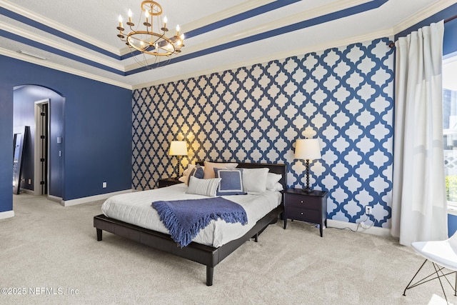 carpeted bedroom with a raised ceiling, ornamental molding, arched walkways, wallpapered walls, and baseboards