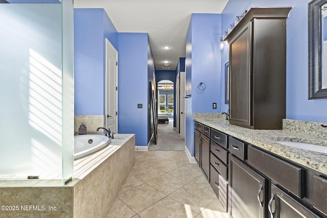 full bathroom featuring tile patterned flooring, double vanity, a garden tub, and a sink