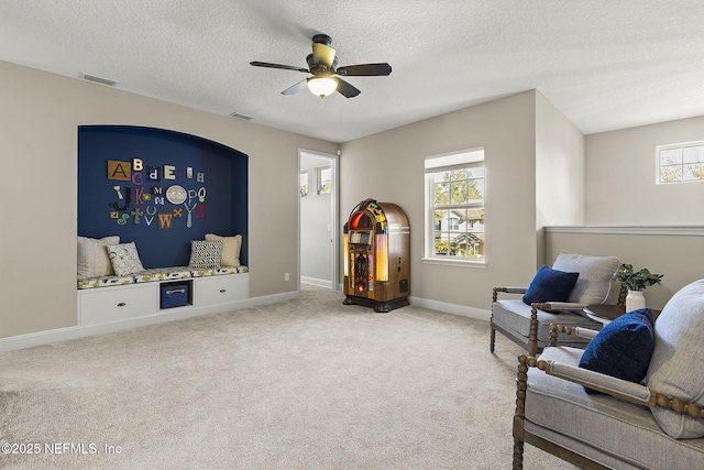 living area featuring visible vents, baseboards, carpet, and a healthy amount of sunlight