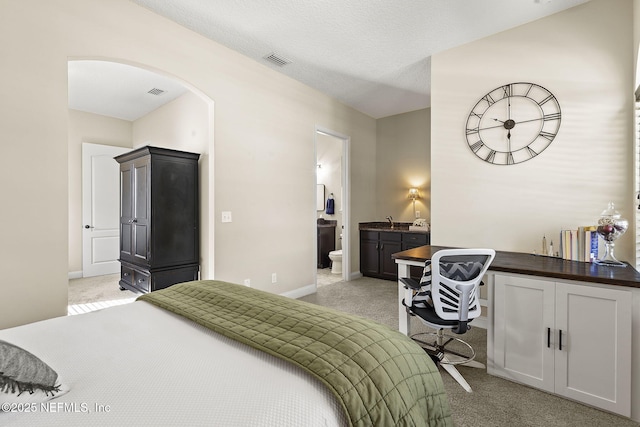 bedroom with baseboards, visible vents, arched walkways, a textured ceiling, and light carpet