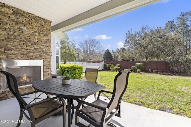 view of patio / terrace featuring outdoor dining area, an outdoor stone fireplace, and a fenced backyard