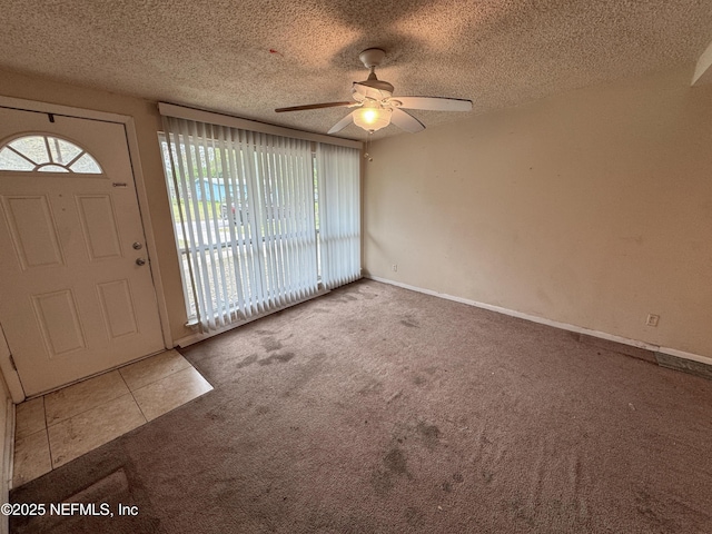 tiled entryway with a textured ceiling, a ceiling fan, and carpet floors