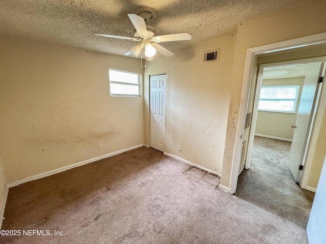 unfurnished bedroom with a closet, visible vents, multiple windows, and a textured ceiling