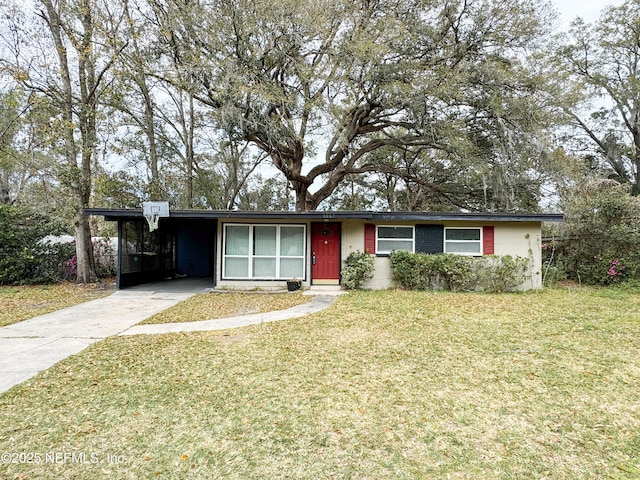 ranch-style home featuring a carport, concrete block siding, a front lawn, and driveway