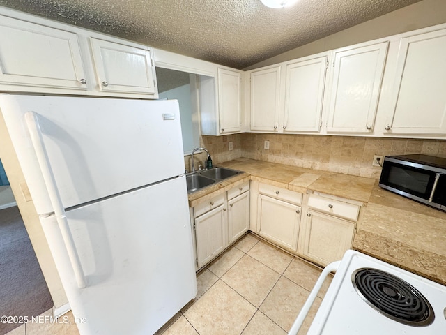 kitchen with freestanding refrigerator, a sink, stainless steel microwave, range, and tasteful backsplash