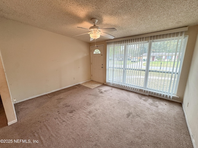 carpeted empty room featuring a ceiling fan, baseboards, and a textured ceiling