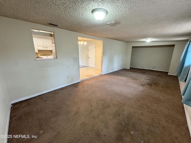 carpeted empty room with visible vents, a textured ceiling, and baseboards