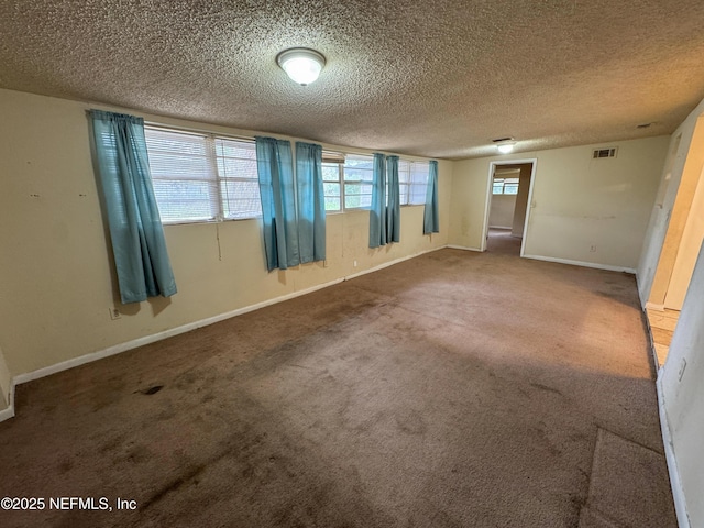 unfurnished room featuring visible vents, carpet, baseboards, and a textured ceiling