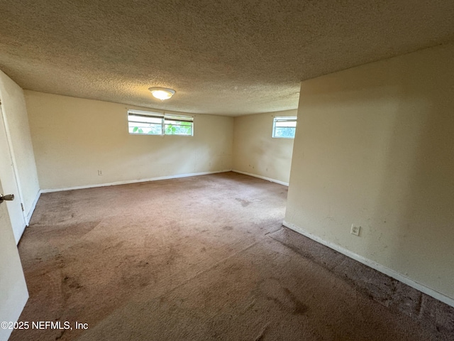 basement with carpet, baseboards, a wealth of natural light, and a textured ceiling