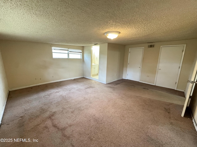 unfurnished bedroom featuring light carpet, visible vents, a textured ceiling, and baseboards