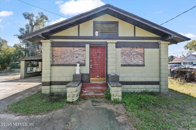 view of front of property with a carport, concrete driveway, and concrete block siding