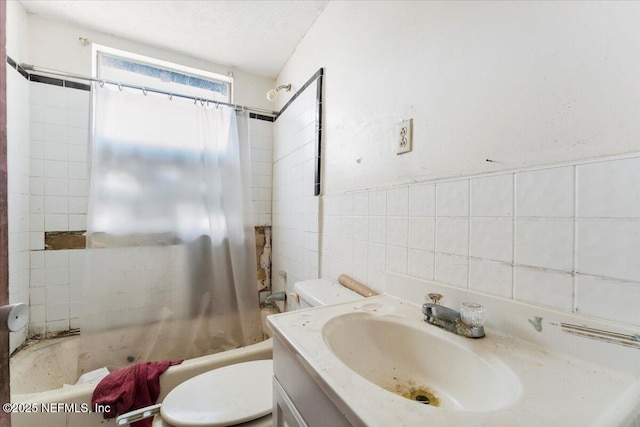 full bath with vanity, shower / bath combo with shower curtain, a textured ceiling, tile walls, and toilet