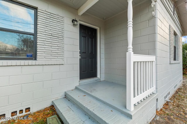 view of exterior entry featuring crawl space and concrete block siding