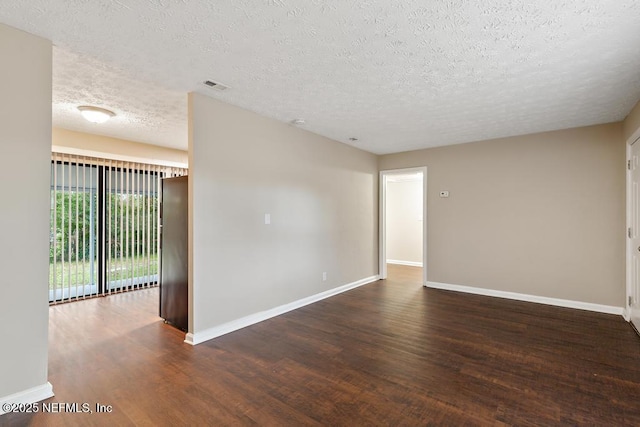 unfurnished room featuring a textured ceiling, wood finished floors, visible vents, and baseboards