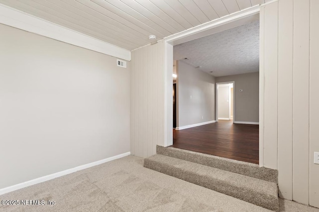 empty room with visible vents, a textured ceiling, baseboards, and carpet floors