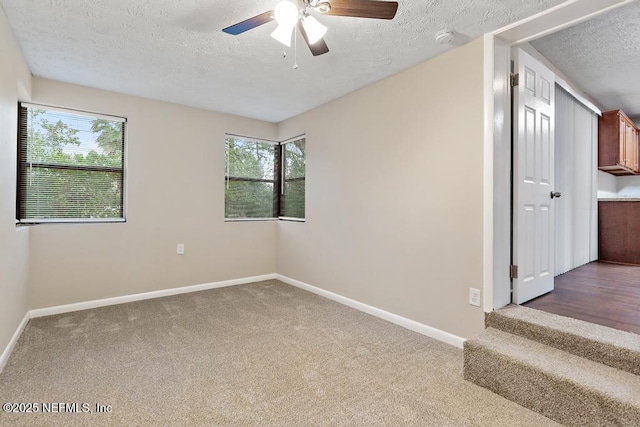 unfurnished room with ceiling fan, baseboards, carpet floors, and a textured ceiling