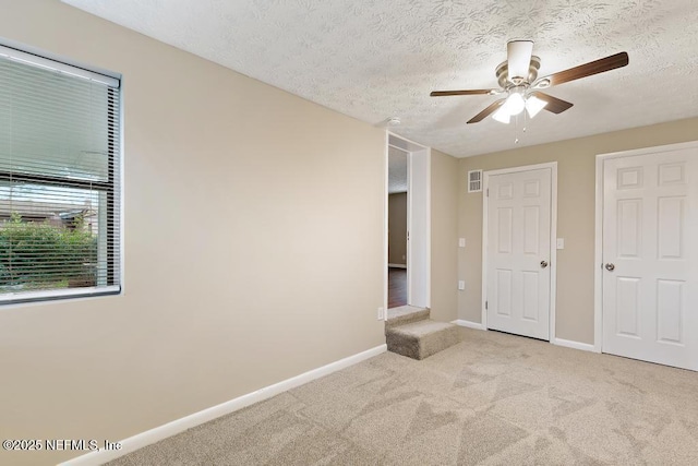 unfurnished bedroom with carpet flooring, visible vents, baseboards, and a textured ceiling