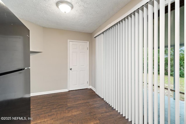 corridor featuring wood finished floors, baseboards, and a textured ceiling