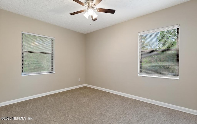 empty room with carpet flooring, a ceiling fan, baseboards, and a textured ceiling