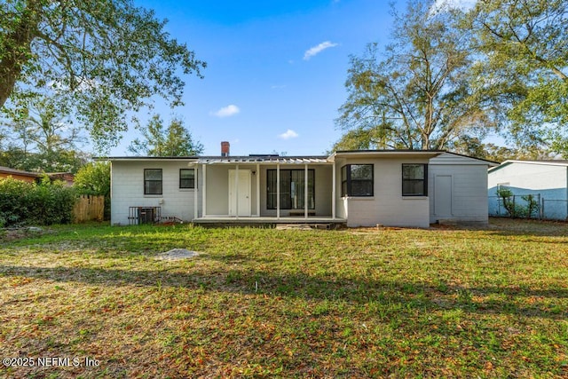 back of house featuring a lawn, concrete block siding, and fence