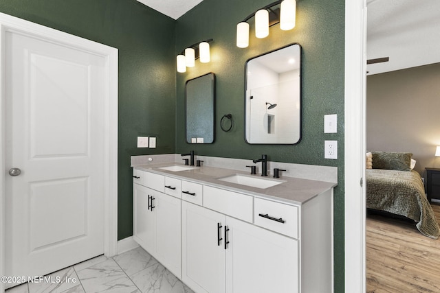 bathroom featuring a sink, marble finish floor, ensuite bathroom, and double vanity