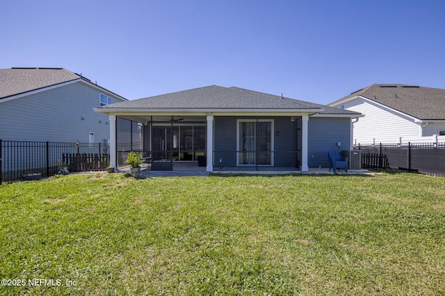 rear view of house featuring a lawn, a fenced backyard, and a sunroom