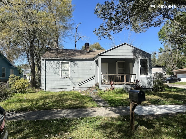 view of front of home with a front lawn, covered porch, and a chimney