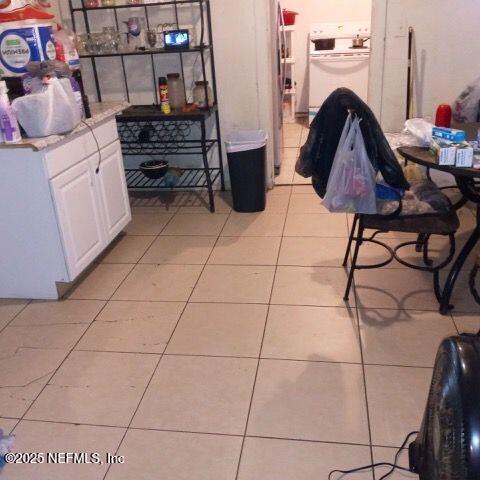 interior space featuring light countertops, white cabinets, light tile patterned floors, and range