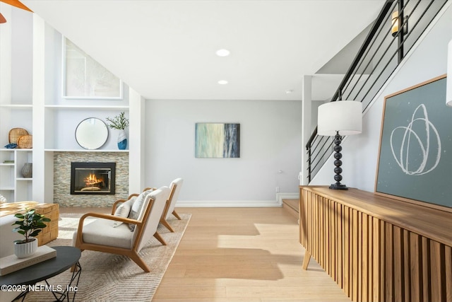 living area featuring stairway, baseboards, recessed lighting, a fireplace, and light wood-type flooring